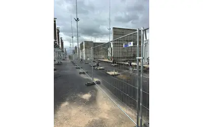 גידור זמני באתר תחנת משנה עם קירות בטון וציוד חשמלי
